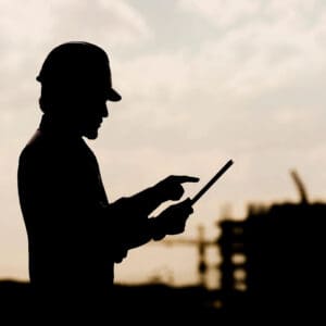 A man in hard hat holding a tablet.