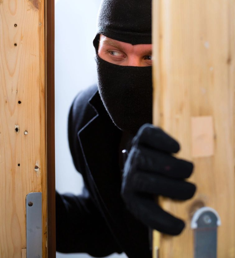 A man in black mask and gloves opening door.